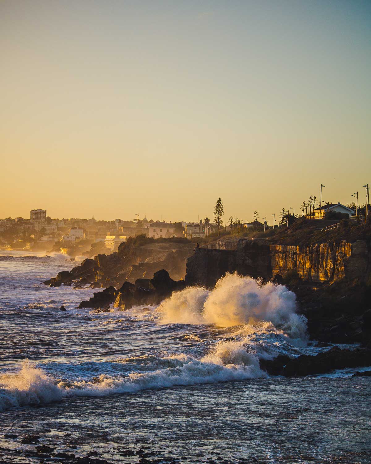 Weekend breaks in Portugal | 10 Perfect locations to visit in Portugal 15 Some of the best day trips from Lisbon is Estoril and the magical promenade in this photo with the waves on the high cliffs and the city in the background