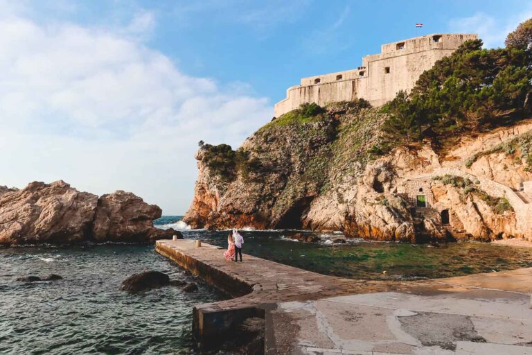 Dubrovnik West Harbour is a quintessential place to discover in Dubrovnik. Away from the crowds of the old town, you need to get lost in the narrow streets outside the city walls, Fort Lovrijenac on the background and awesome blue turquoise water with a fantastic beach in Dubrovnik - Is Dubrovnik worth visiting? Discover the incredible reasons to visit Dubrovnik