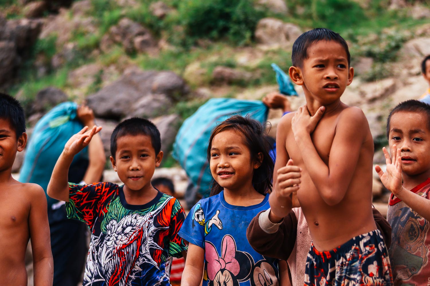 Unveiling the hidden gems: An unforgettable Laos itinerary 2 weeks 8 Kids playing on the Mekong River - Waving at the boat approaching the shore